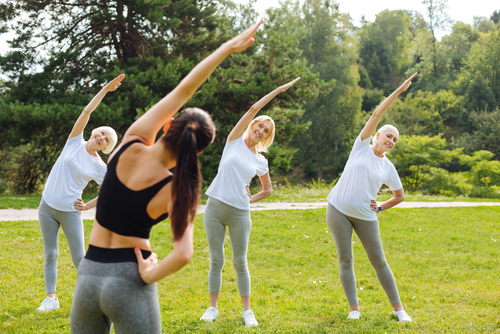 three healthy elderly women exercising with a young female coach